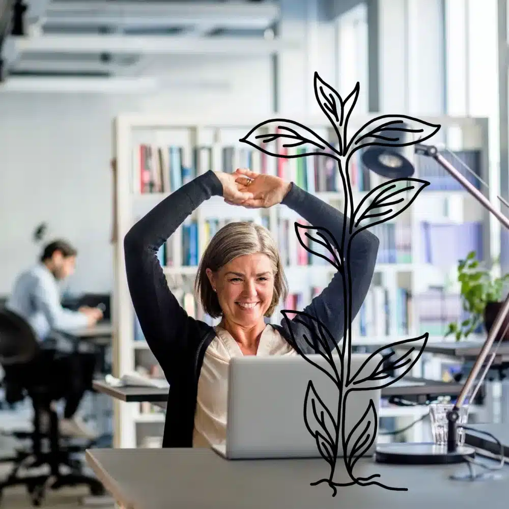 A woman embraces flexwork at her office desk, smiling while stretching with arms raised behind her head. A digital illustration of a plant overlays the image. In the background, a coworker is engaged at another desk, with shelves and a window enhancing the serene scene.